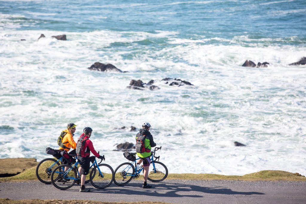 Three people cycling along the coast